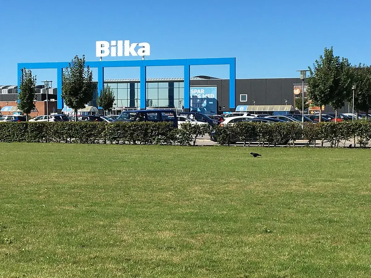 Bilka supermarket building with parking lot and grassy foreground.