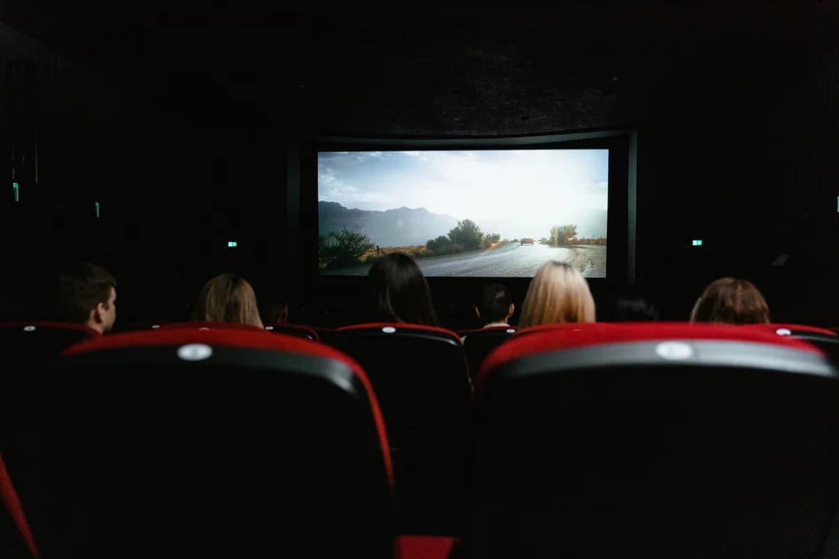 back view of people watching movie in theater with red seats