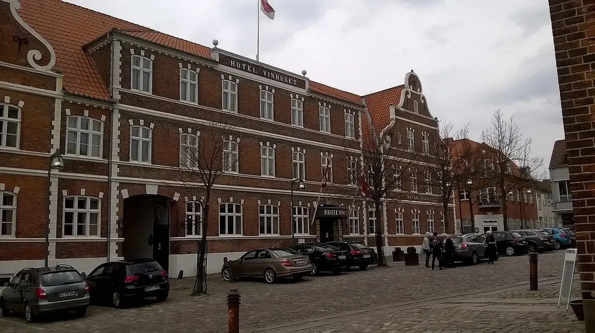 Historic Hotel Vinhuset building in Næstved with parked cars in front.