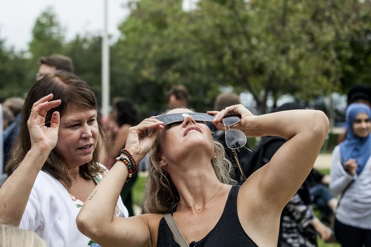 People looking up at the sky wearing solar eclipse glasses during a total solar eclipse