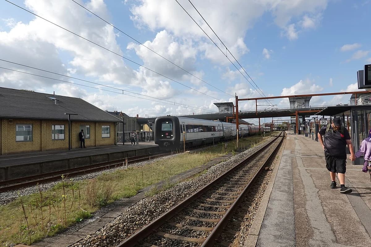 A train at Næstved Station with passengers on the platform.