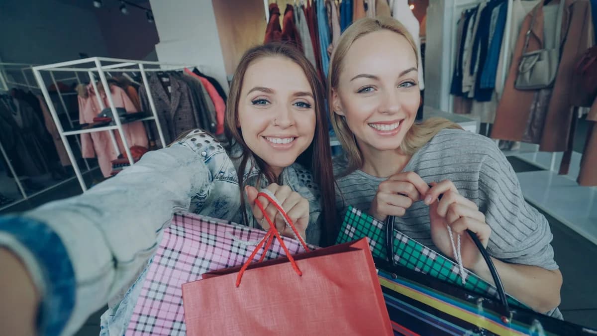Two women smiling with shopping bags in a clothing store