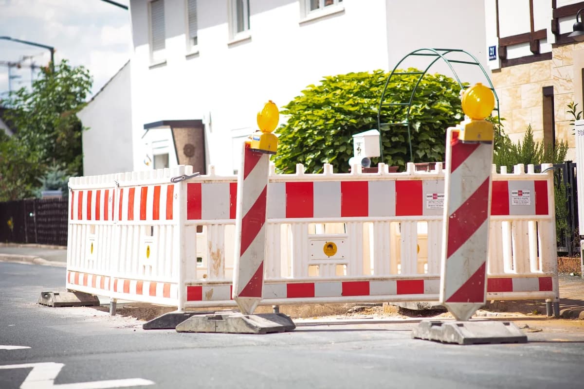 Red-and-white roadwork barricade blocking a suburban street