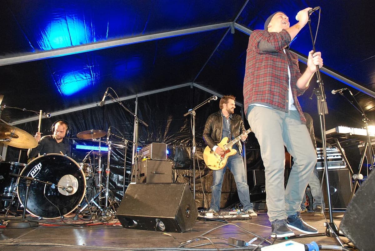 A band performing live on a stage under blue lights.