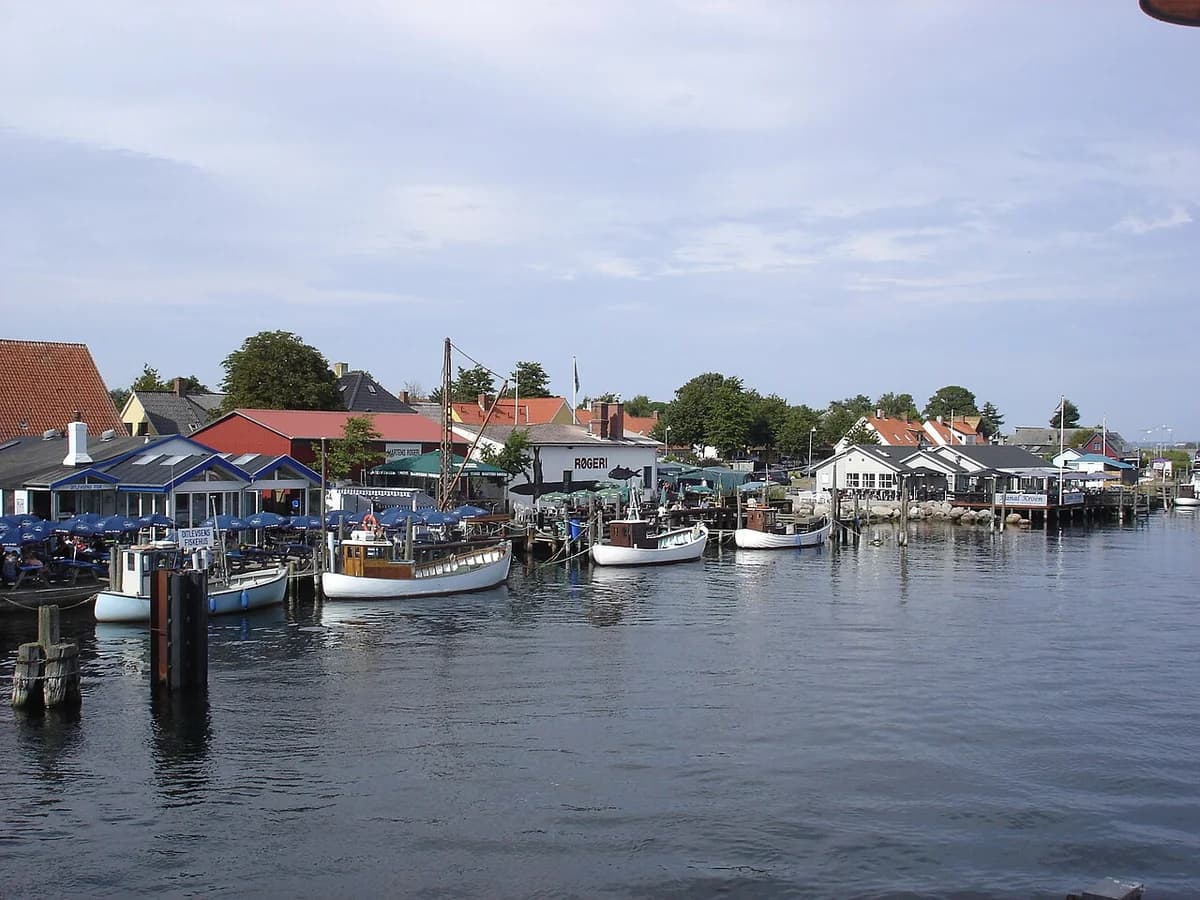 Boats docked along a canal in a Danish harbor with buildings on the waterfront.