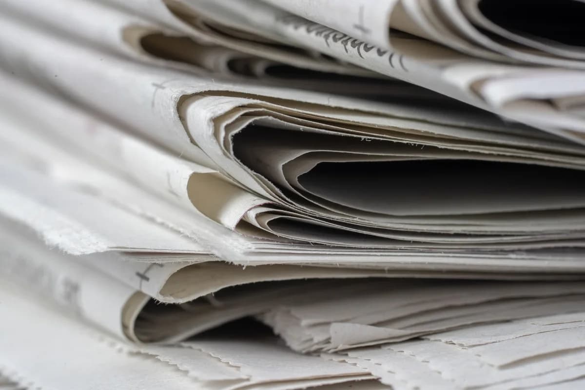 Close-up of stacked newspapers with layered, curled edges.