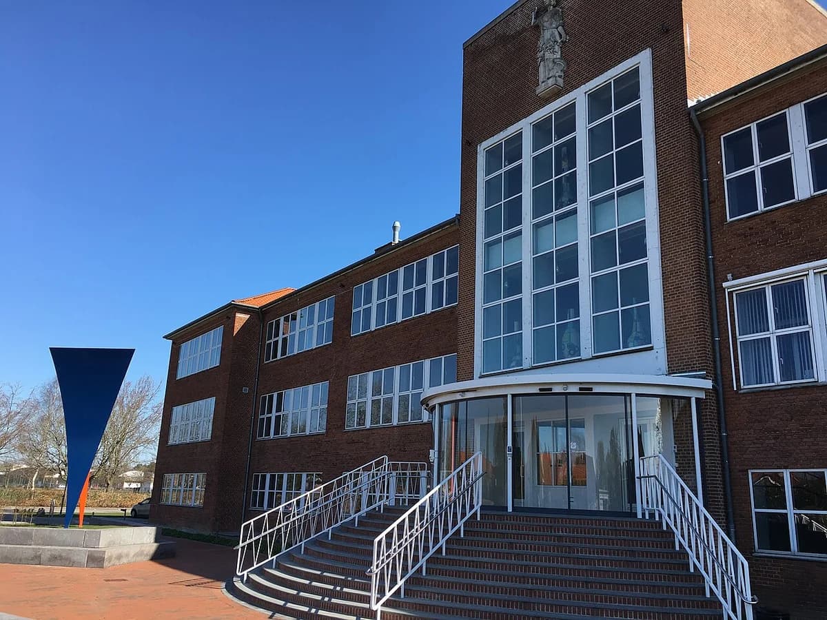 Facade of Næstved Gymnasium building with entrance and steps, blue sky