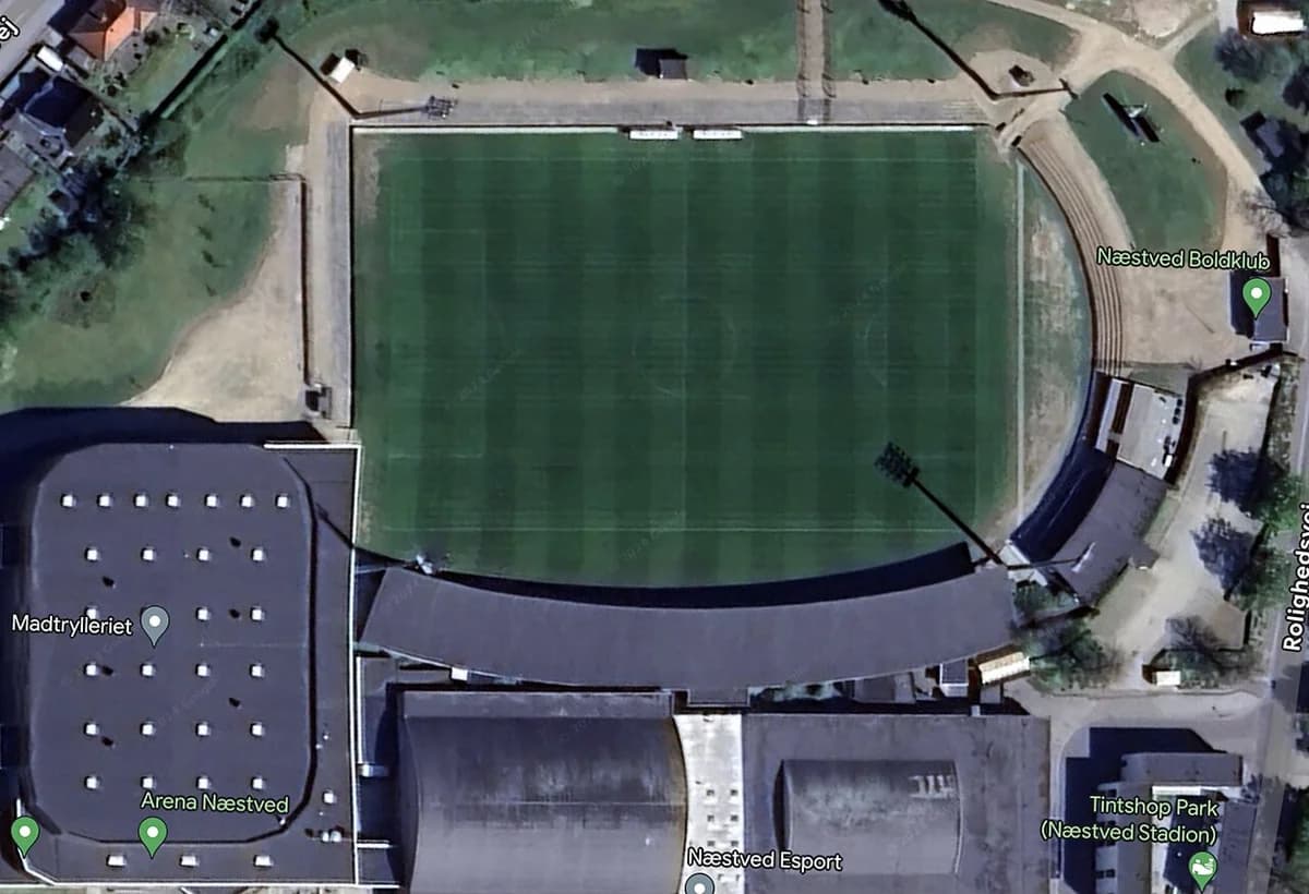 Aerial view of Næstved Stadium with adjacent buildings and green field