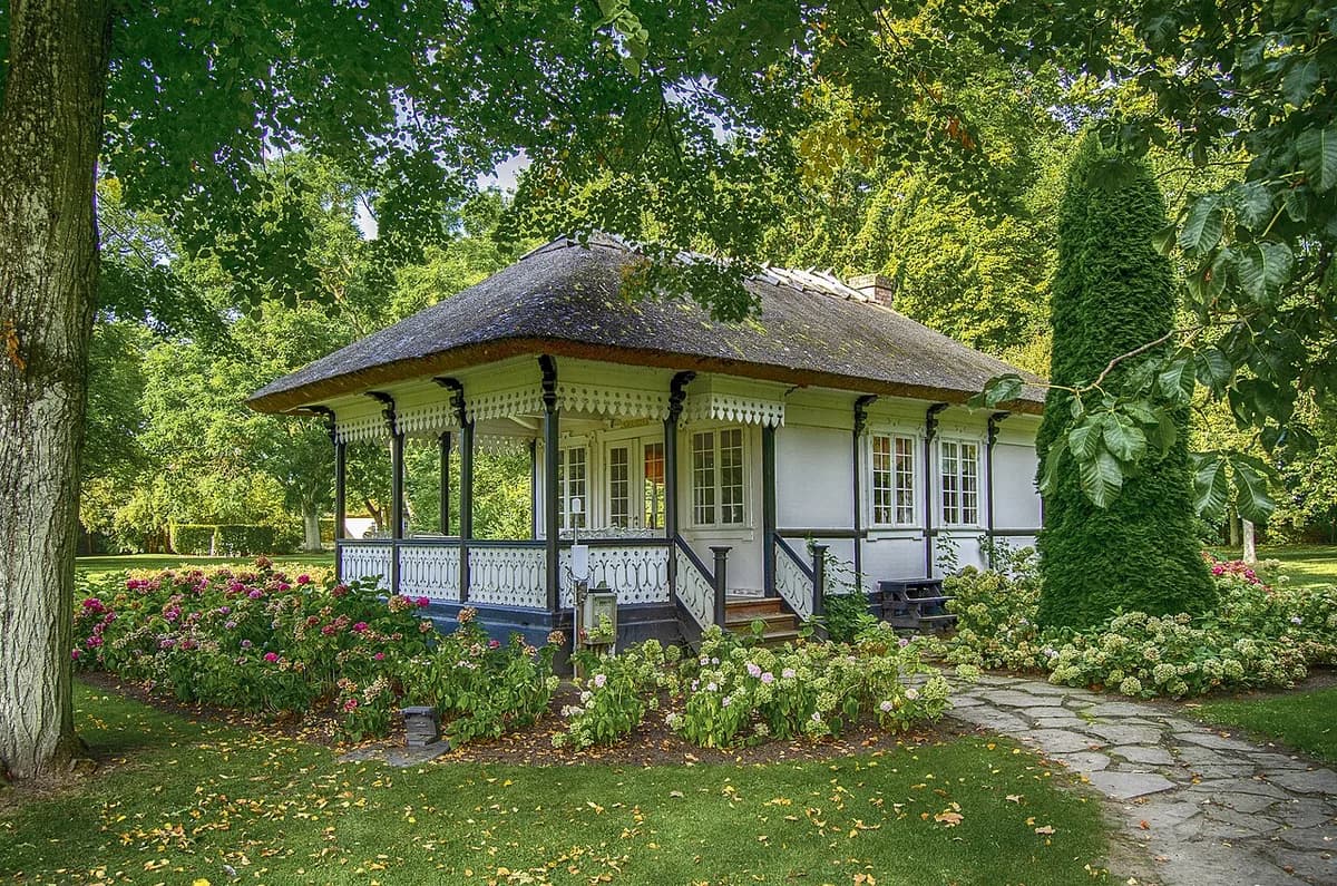 A small pavilion in a landscaped garden with flowers and trees.