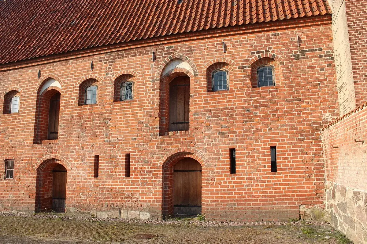 Rear view of a historic red brick building with arched doors and windows in Næstved.