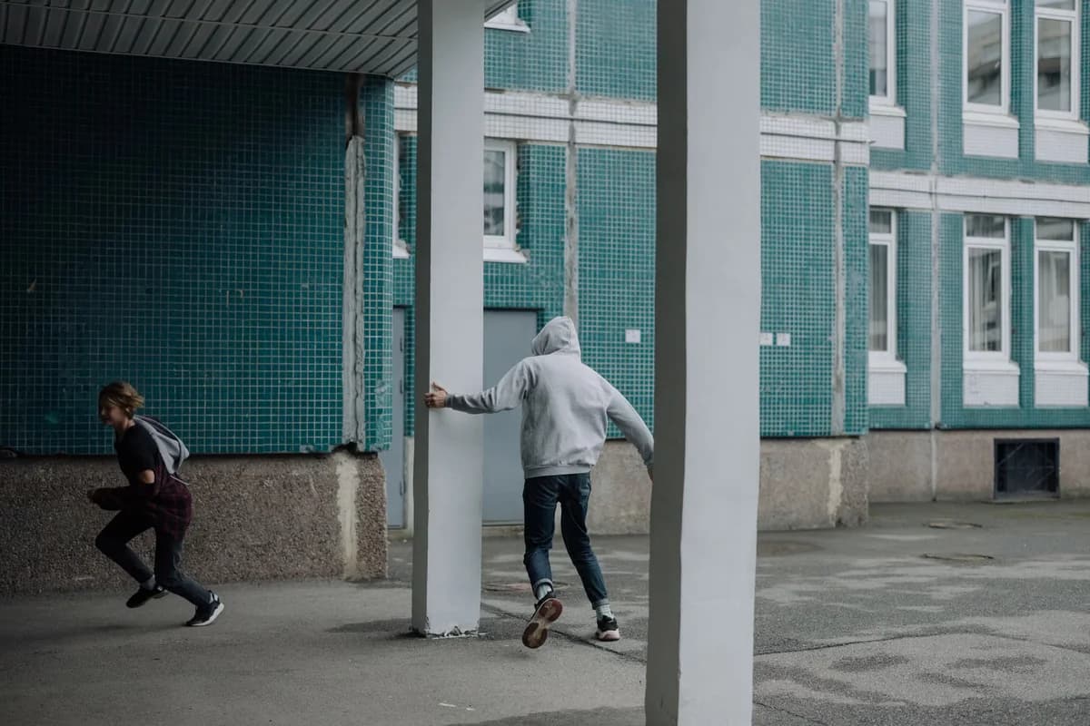 teenagers playing tag near a blue building