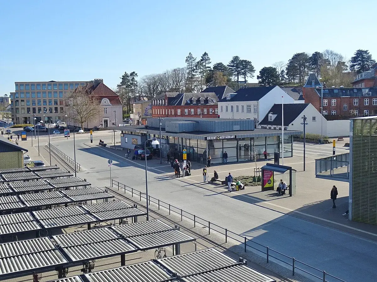 Bus station area near Næstved Station in Denmark with people and buildings.