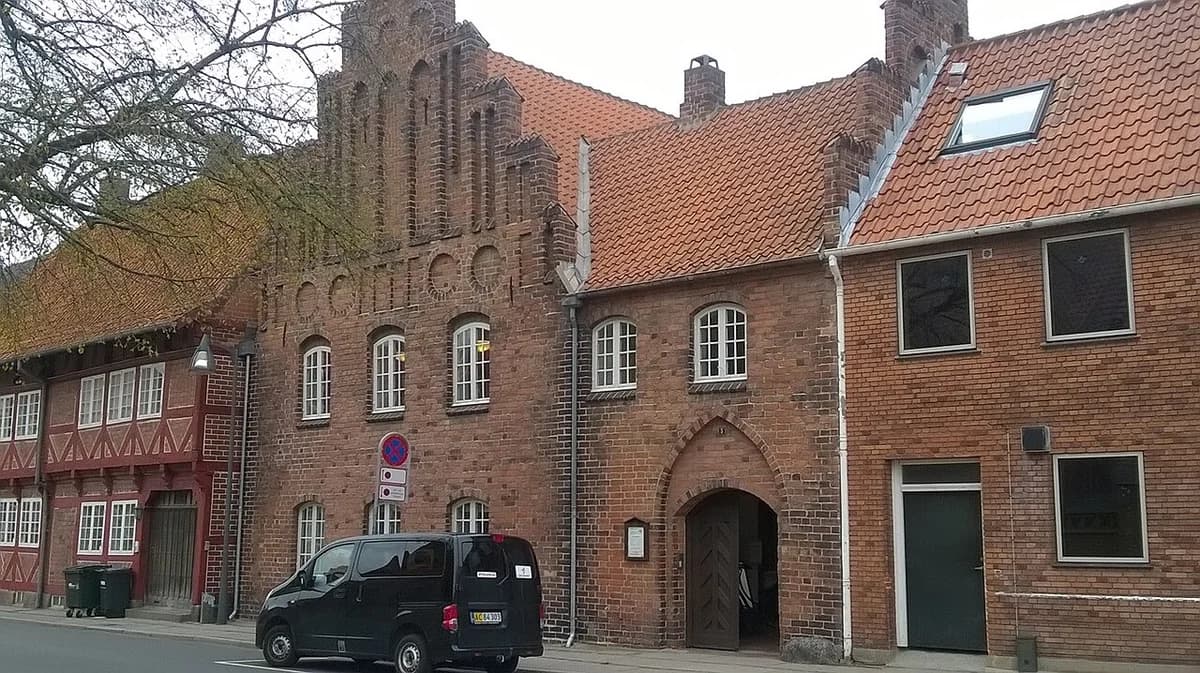 Historic brick town hall building on a street with a parked van.