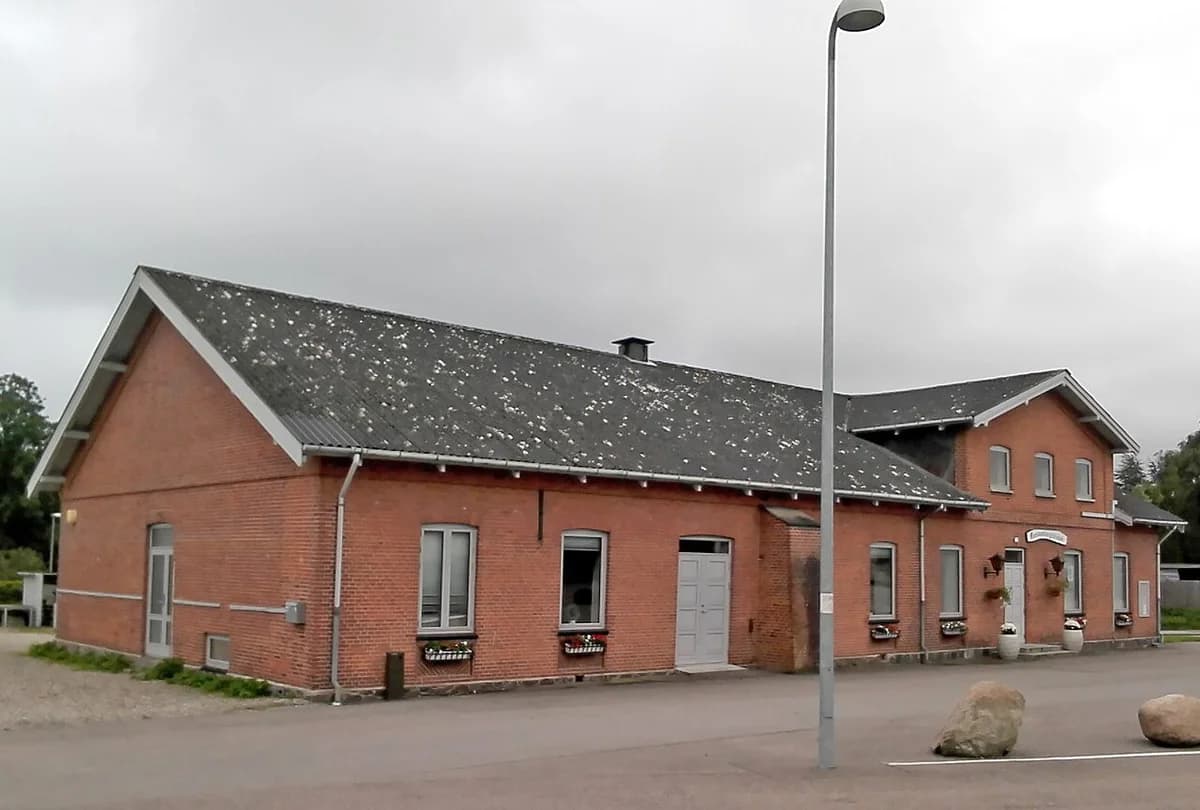 A red brick community house with a pitched roof on an overcast day.