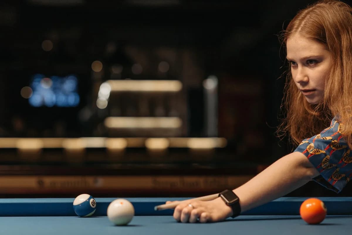 Young woman aiming pool shot on billiards table
