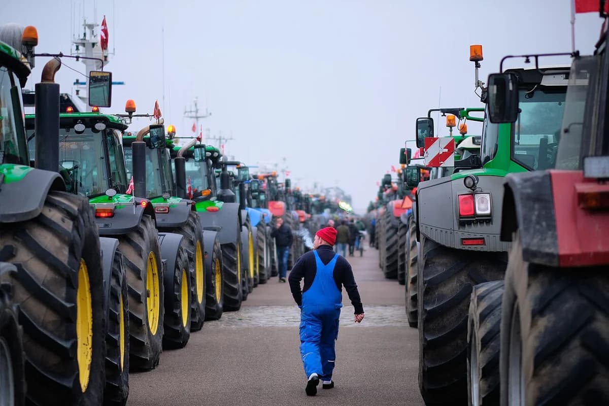Line of tractors parked along a street with a person walking between them in Copenhagen