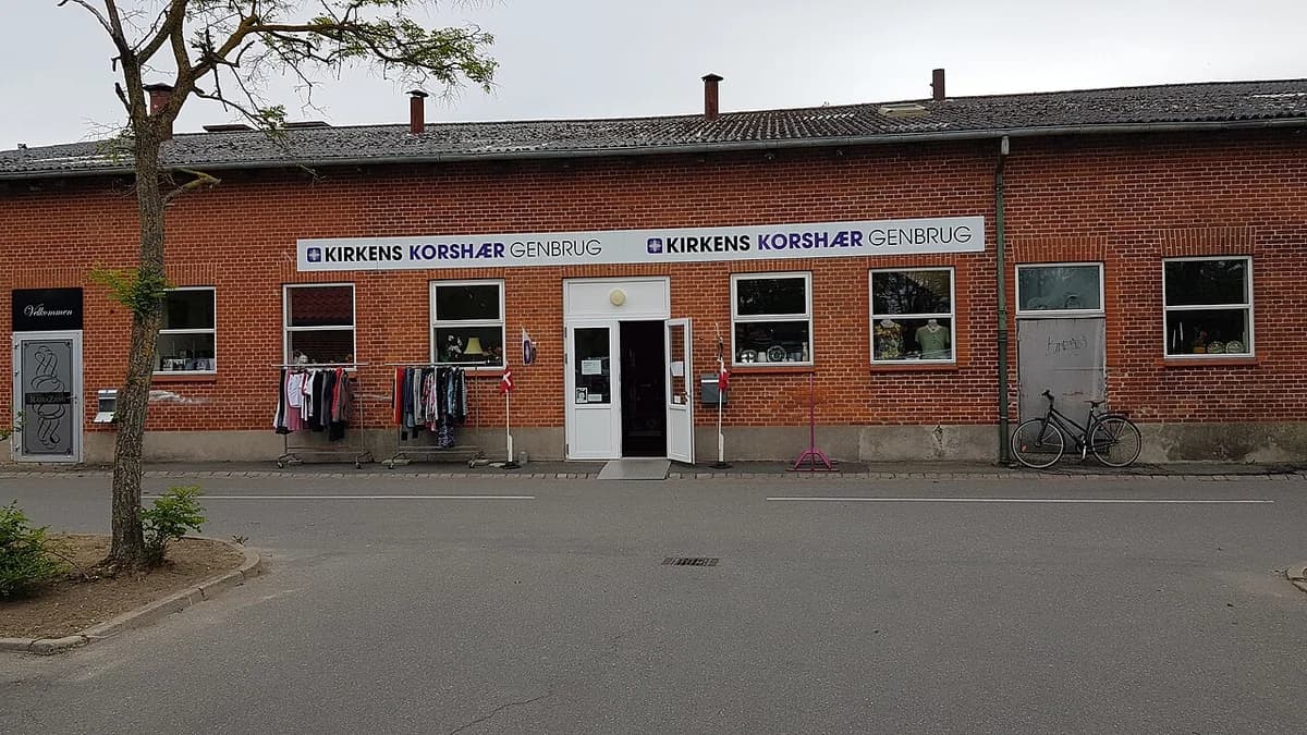Exterior of Kirkens Korshær Genbrug secondhand store in Bogense with clothes racks outside
