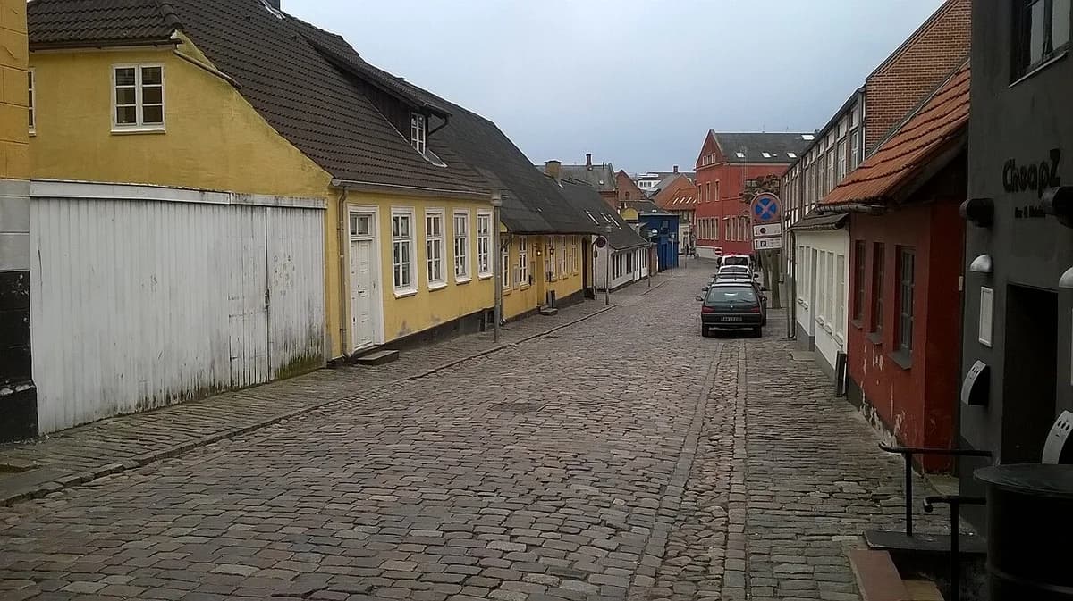 A cobblestone street lined with colorful buildings in Næstved, Denmark.