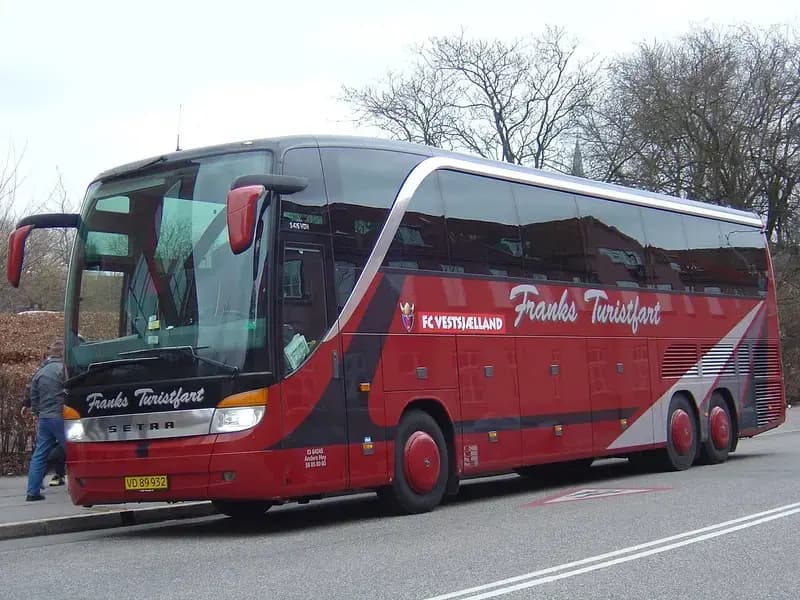 Red and black FC Vestsjælland team bus parked by the curb