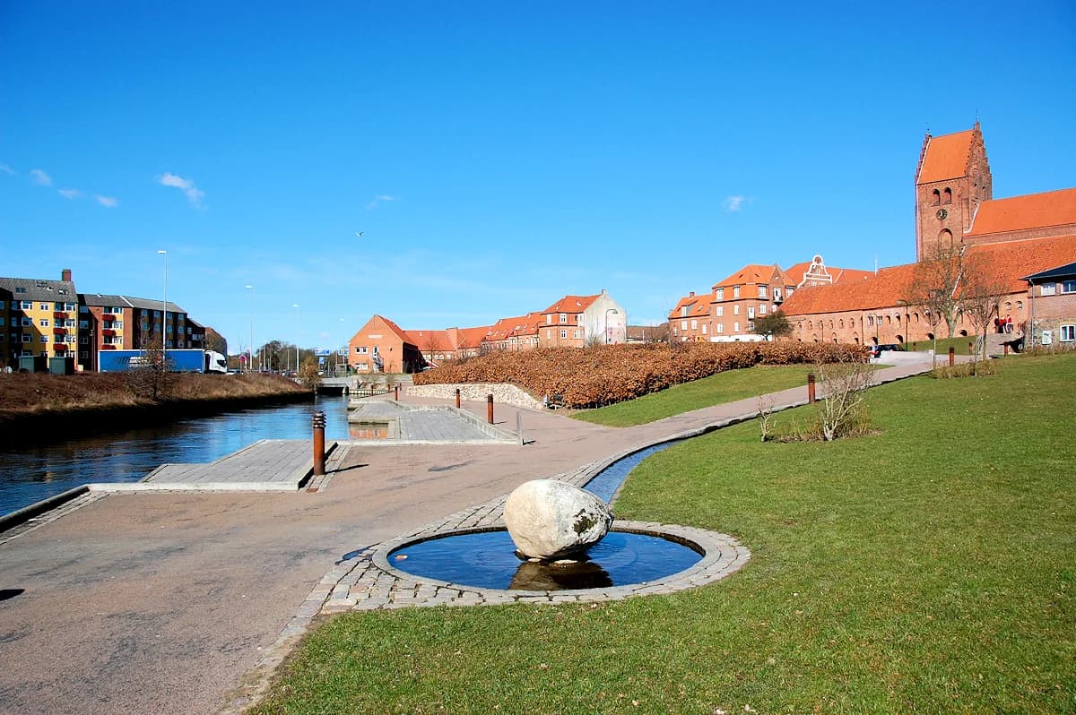 View of Næstved town with red-roofed buildings, a canal, and a water feature
