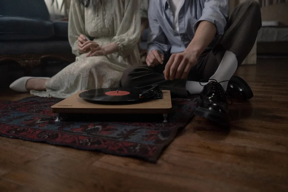 A couple sitting on the floor next to a record player and vinyl record.