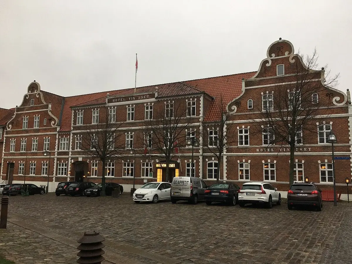 Facade of Hotel Vinhuset in winter with parked cars in front.