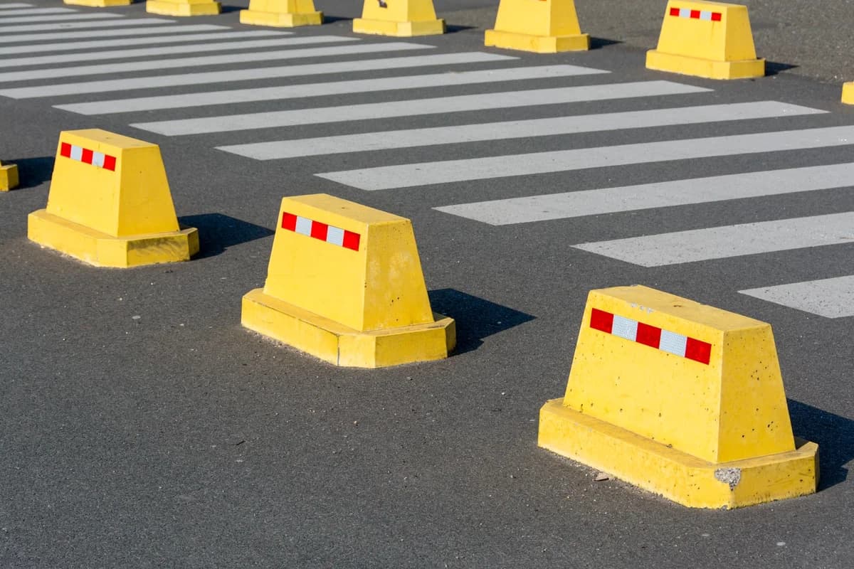 Yellow concrete barriers near pedestrian crossing on asphalt